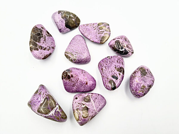 Atlantasite tumbled stones scattered with white background, purple and green gemstone