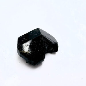 a black crystal on a white surface, black tourmaline