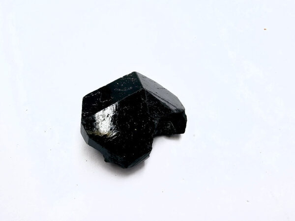 a black crystal on a white surface, black tourmaline